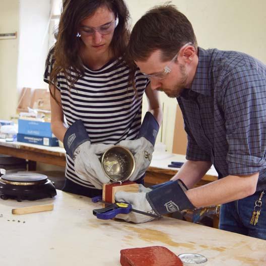 Prof. Bryan Park assists a student in pouring molten metal into a cast for Benedictine College's Discovery Scholar Medal